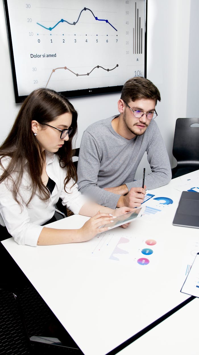 services-03 Two business professionals collaborating on financial analysis with charts and graphs.